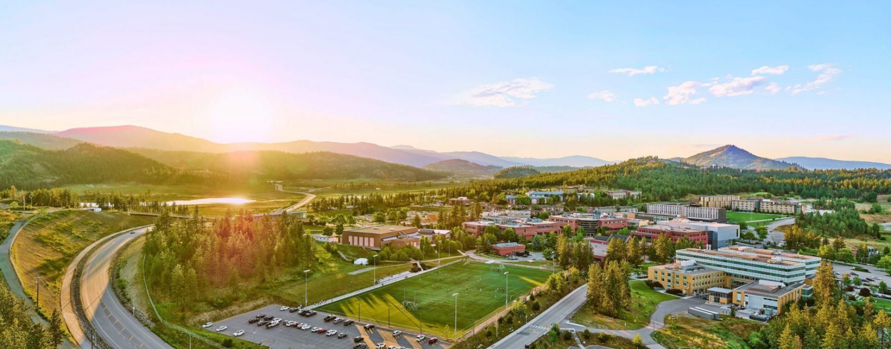 Aerial photo of the UBC Okanagan campus at sunset with campus buildings and mountains in the background